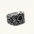 Silver-tone 316L stainless steel signet ring with black enamel spade motif and intricate floral scrollwork relief detail.